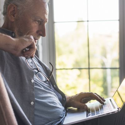 serious-senior-man-using-laptop-home